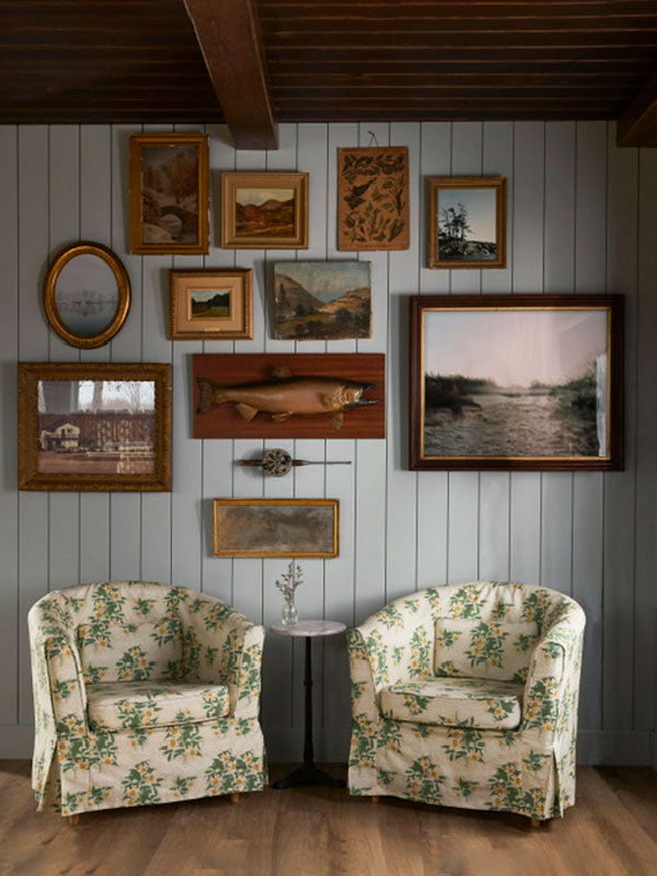 Two floral-patterned chairs in a room with framed artwork on the wall.
