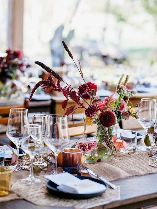 Decorative table setting with flowers, glasses, and cutlery.