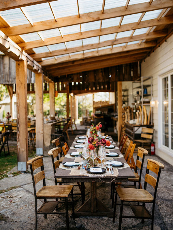 Dining table set for a meal under a wooden pergola