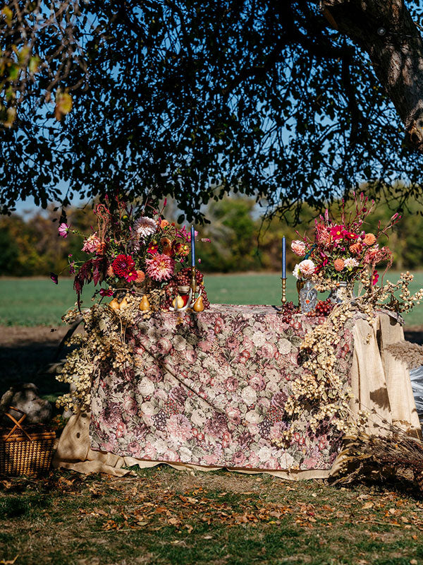 Decorative table with floral arrangements outdoors under a tree