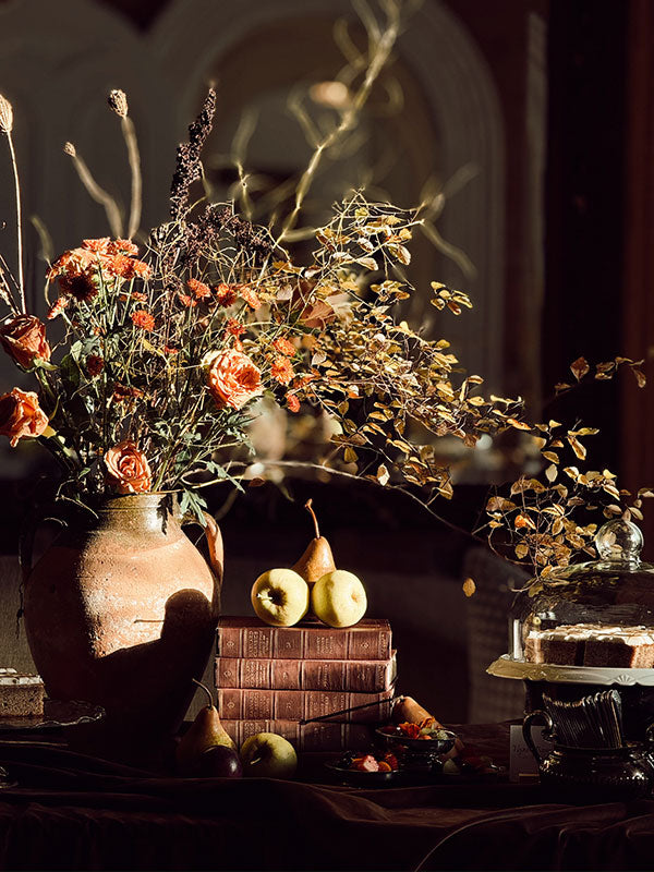 Decorative still life with flowers, pears, and books in a dark setting