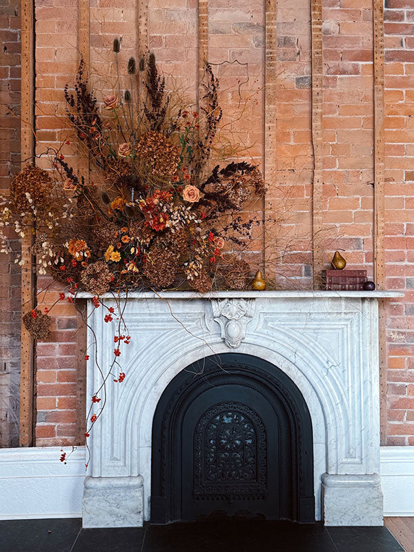 Decorative fireplace with dried flowers and a brick wall background