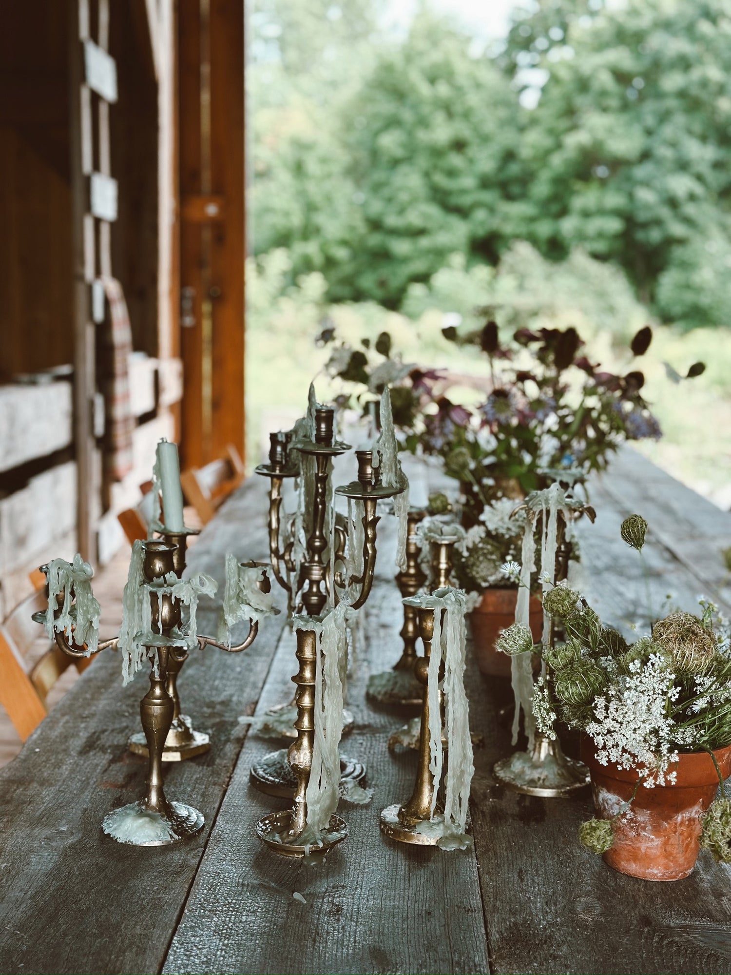 Decorative table setting with candelabras and potted plants outdoors