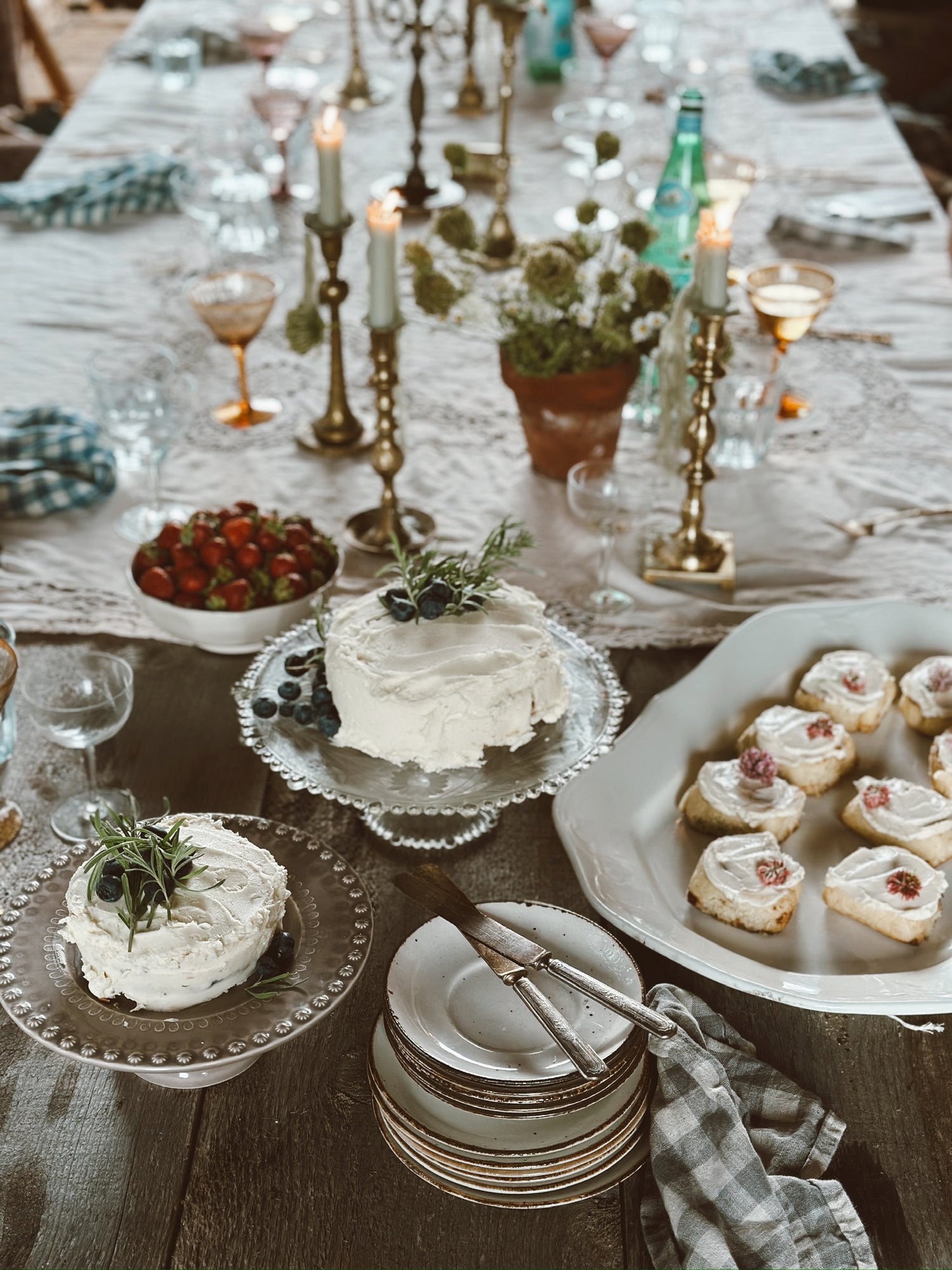 Dining table set with a cake, plates, and various dishes on a checkered tablecloth.