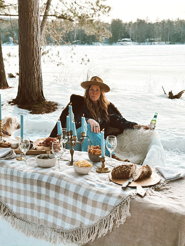 Christine sitting at a table set for a meal in a snowy outdoor setting.