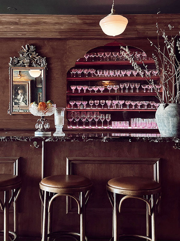 Bar interior with wine glasses on shelves and bar stools.