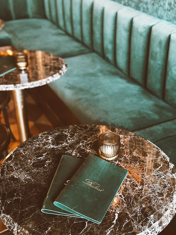 Bar Duchess menu on a marble table with a green banquette in the background