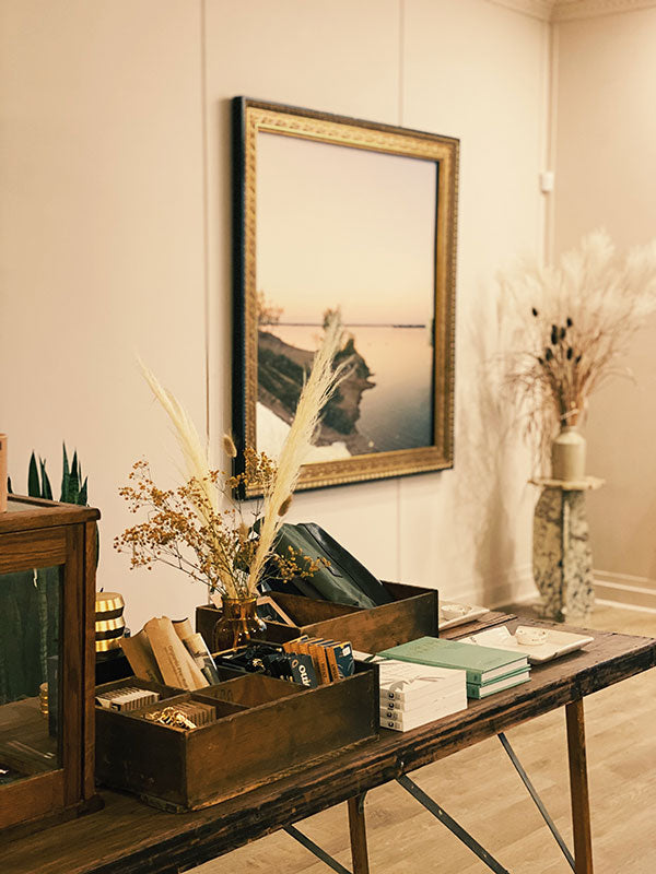 Decorative interior setting with a wooden table, books, and a framed picture on a wall.