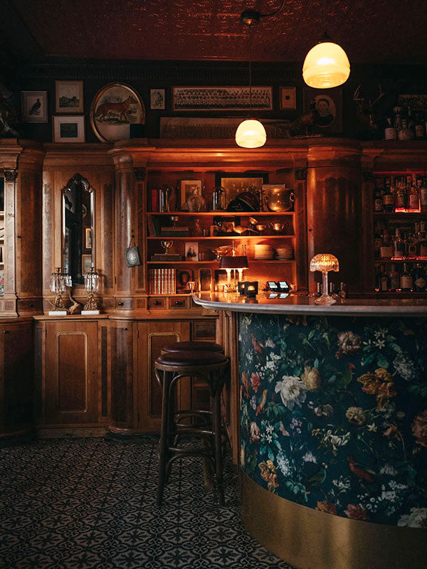 Dark and cozy bar interior with wooden furniture and floral-patterned bar counter.
