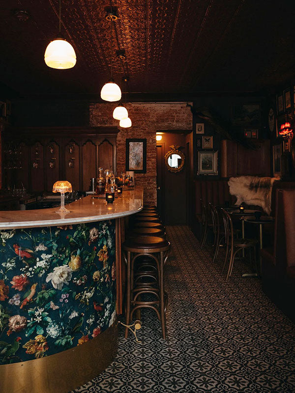 Dark and cozy bar interior with floral-patterned bar and vintage decor.