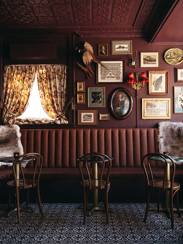 Vintage-style interior with dark wood paneling, framed pictures, and patterned floor tiles.