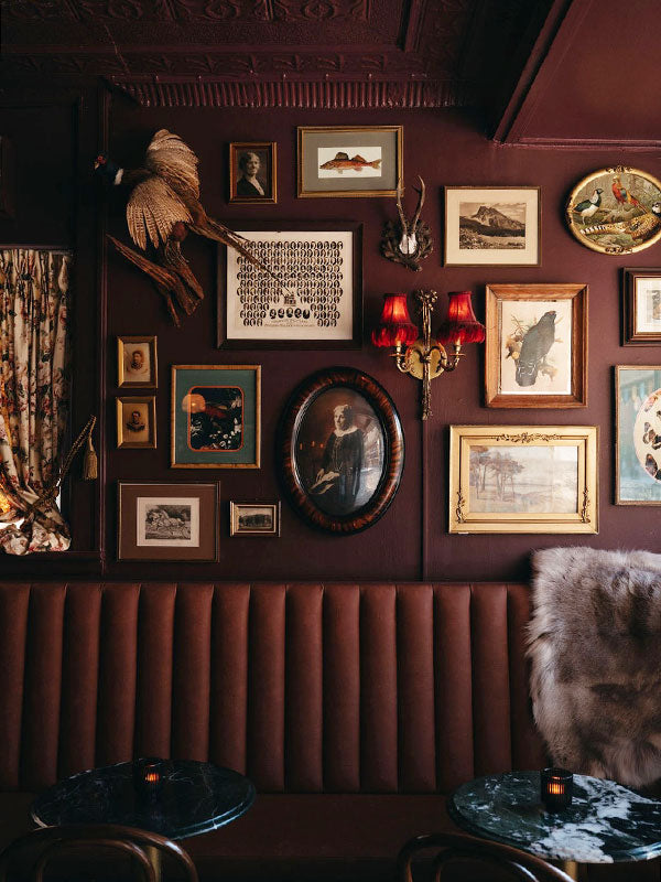 Decorative wall with framed pictures and a sconce at Russ and Co.