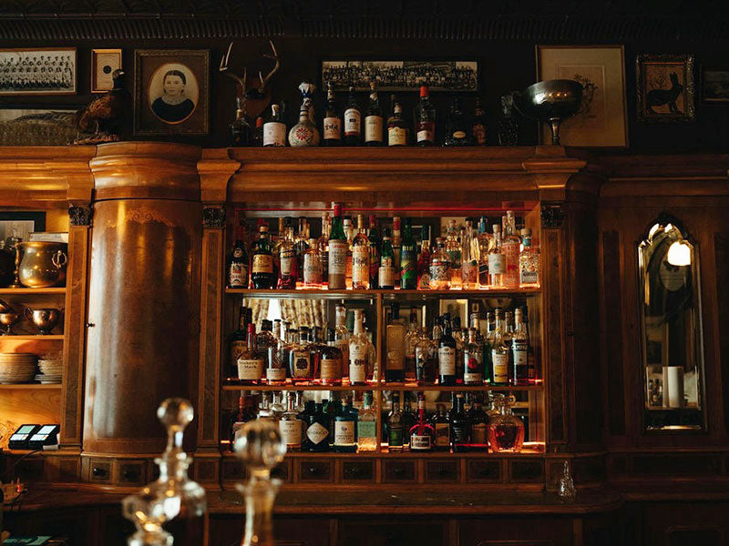 Wooden back bar with shelves filled with various bottles and glasses.