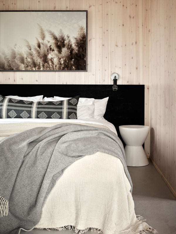 Bedroom with a bed featuring gray and white bedding, a black headboard, and art by Christine Flynn.