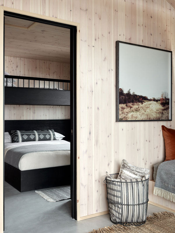 Modern bedroom with wooden walls, a bed, and art by Christine Flynn.