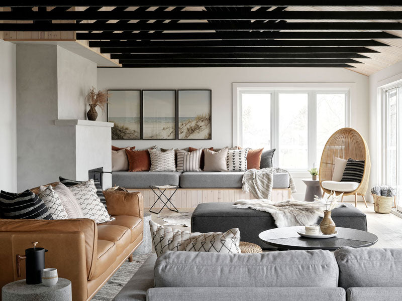 Modern living room with gray sofas, brown leather sofa, and art by Christine Flynn.